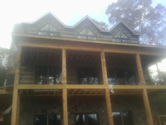 Dormers and porch framing on a large log home under construction — Roof Coating work by our crew in Fairfield