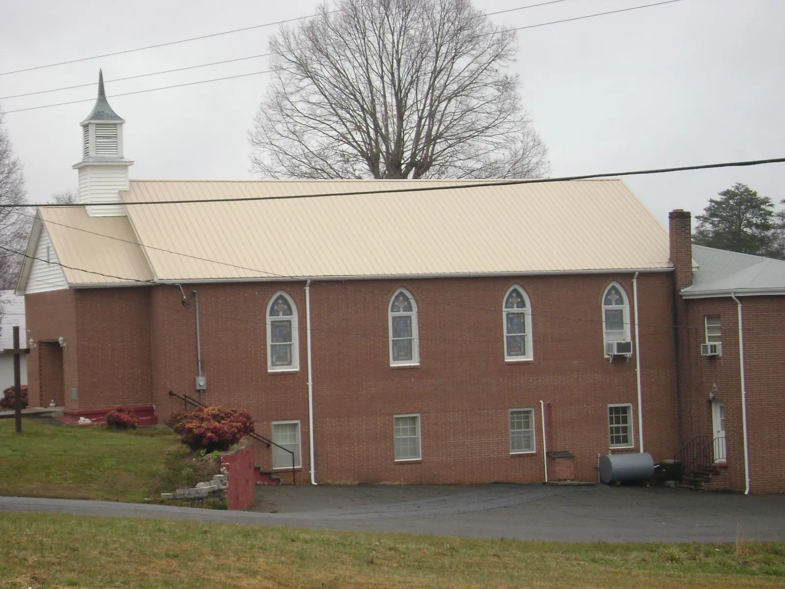 New tan metal roof on a brick church with a white steeple in Fairfield